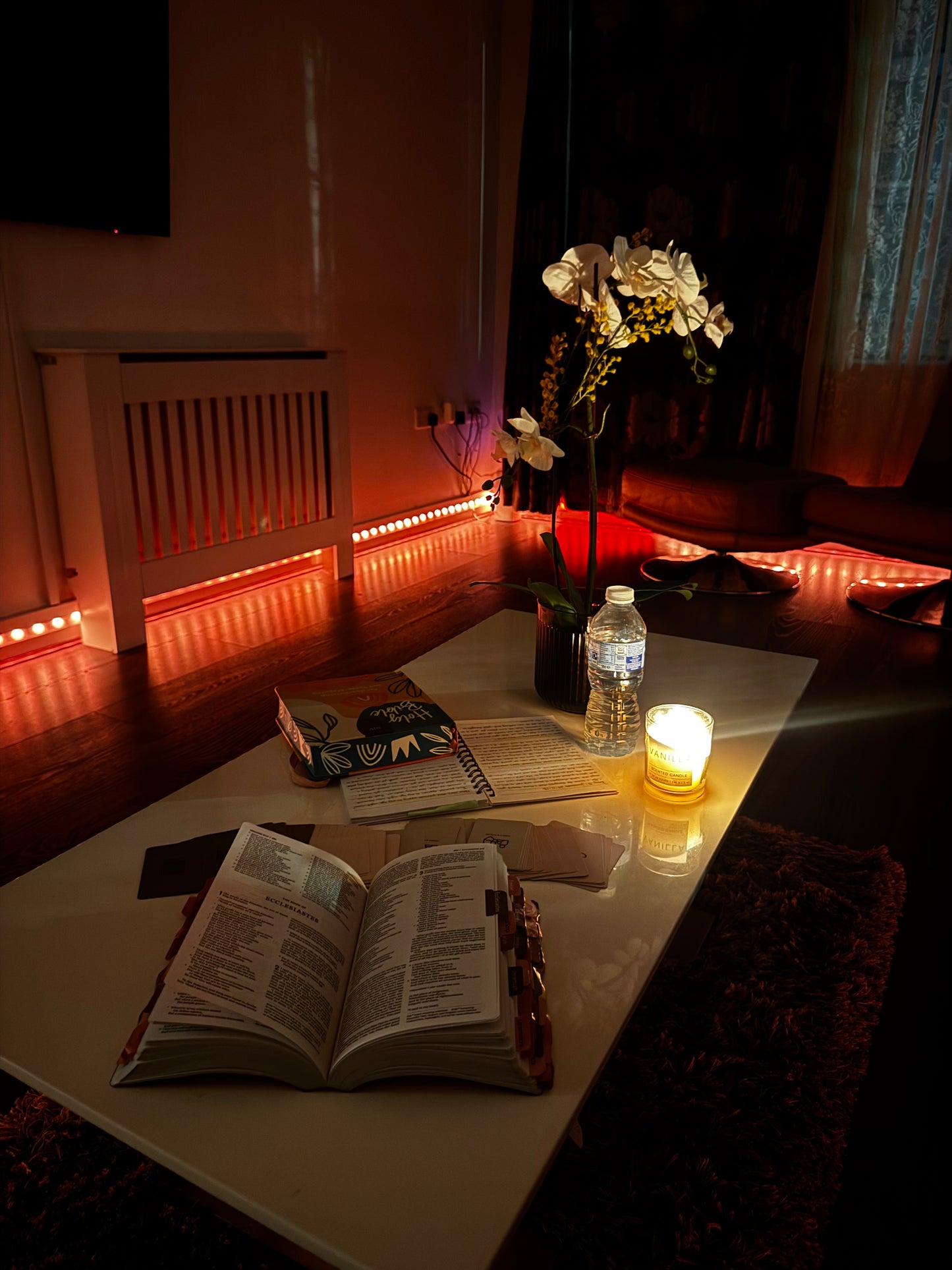 Faith journaling and card game setup with candle on bed